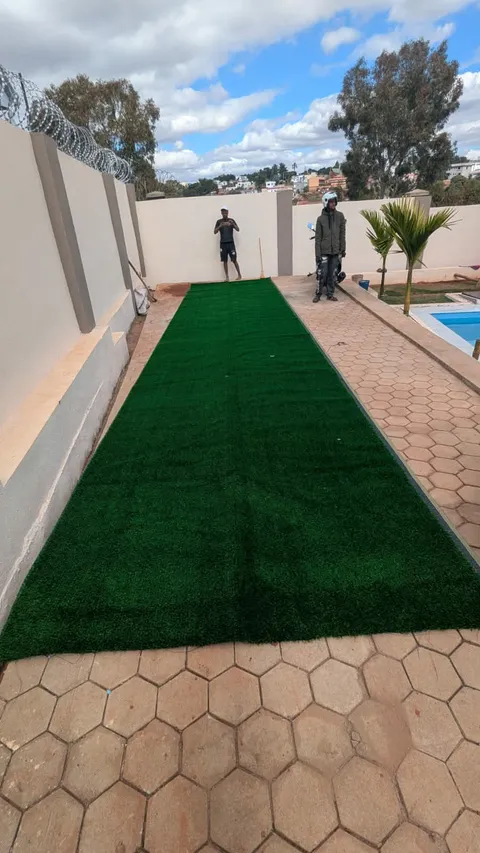 Allée de gazon synthétique au bord d'une piscine